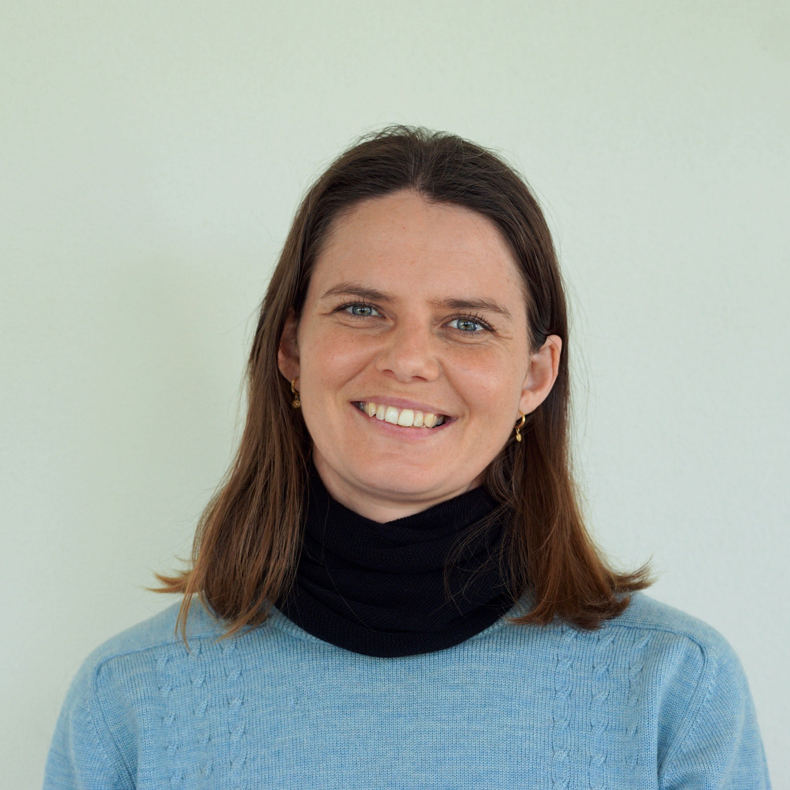 Woman wearing a black scarf and blue sweater against a white background