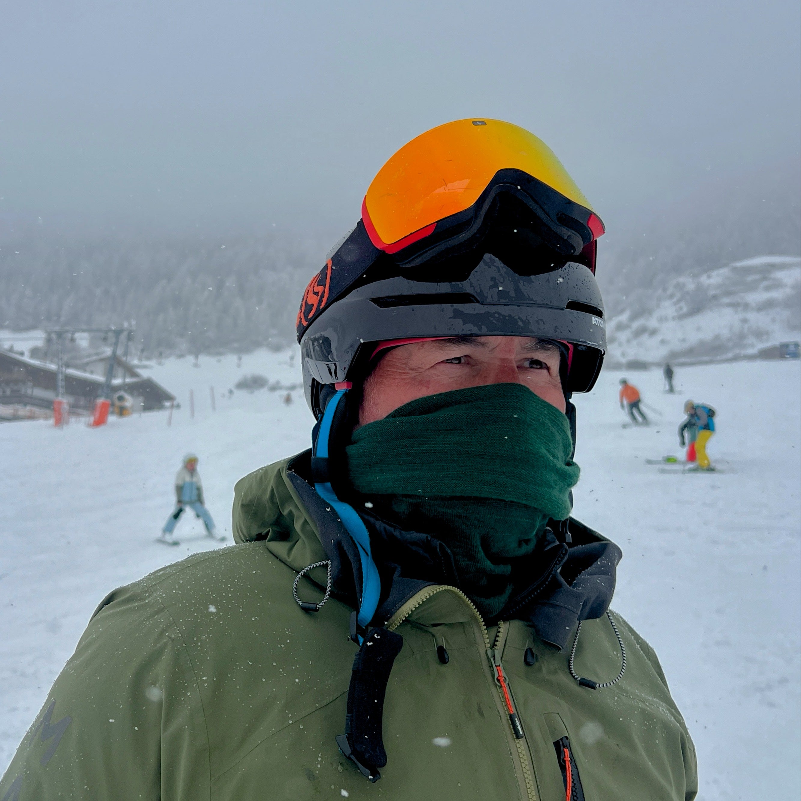 Person in ski gear with a snowy landscape and skiers in the background